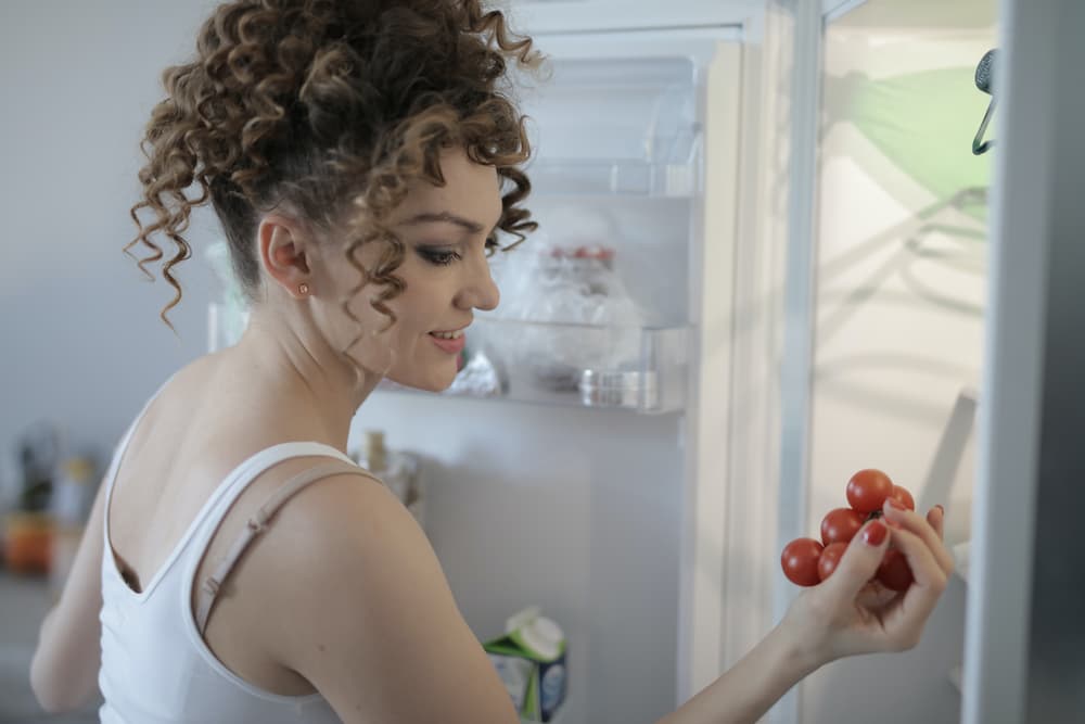 Mulher pegando uma fruta da geladeira